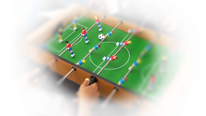 Image shows someone playing table football. the image is framed with a blurred white area, to represent what someone with RP might see.