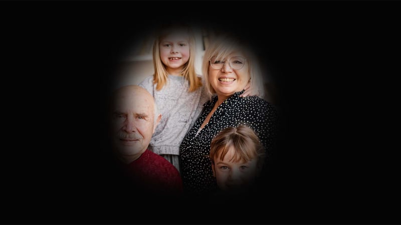Image of a smiling family of four. However, the majority of the image is black, with a small circle in the centre. this has blurred edges, and inside the circle is the family's faces.  