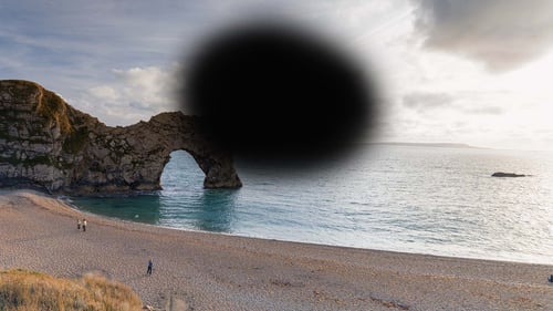 Image of Durdle Door - a rock arch in the sea on the Dorset coast.  Part of the image is obscured by a large black blob shape, with blurred outlines. This represents how a person with AMD experiences seeing this scene
